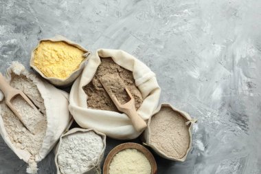 Gri desenli masa ve düz yatak üzerinde farklı tipte un torbaları. Metin için boşluk