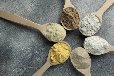 Gri masadaki kaşıklarda farklı türde un, düz.