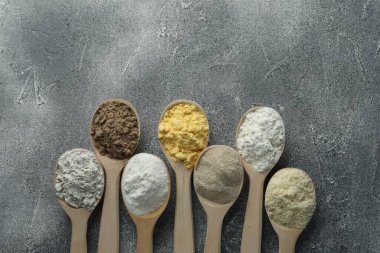 Gri masadaki kaşıklarda farklı türde un, düz. Metin için boşluk