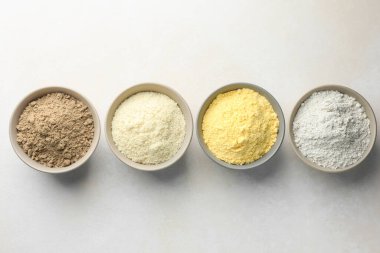 Açık gri masa ve düz tabaklar üzerinde farklı un türleri