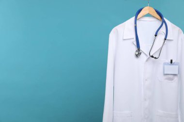 Steteskop ve rozetli doktorun ceketi mavi arka planda. Metin için boşluk