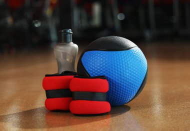 Spor salonunda yerde sağlık topu, şişe ve bilek ağırlıkları. Metin için boşluk