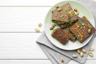 Dubai çikolatası parçaları, beyaz ahşap masa üzerinde şam fıstığı ve knafeh, düz yatıyordu. Metin için boşluk