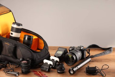 Profesyonel fotoğrafçının ekipmanı ve sırt çantası ahşap masada. Metin için boşluk
