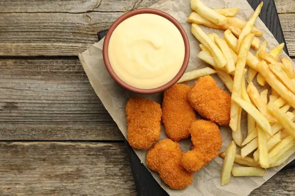 Kasede leziz peynir sosu, tavuk nugget ve ahşap masada patates kızartması, üst manzara. Metin için boşluk