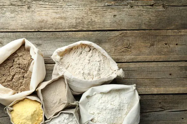 Tahta masadaki poşetlerdeki farklı un türleri, düz yatış. Metin için boşluk