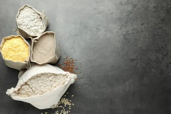 Gri masadaki poşetlerdeki farklı tipte un, düz. Metin için boşluk