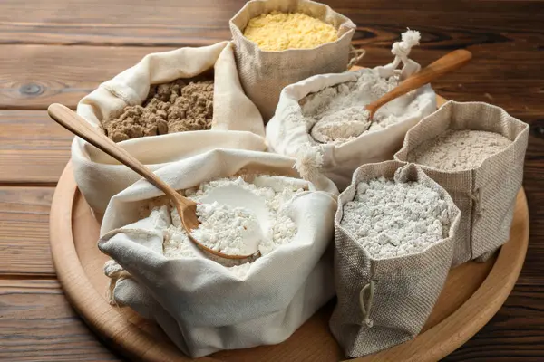 Tahta masadaki poşetlerdeki farklı un türleri, yakın plan.