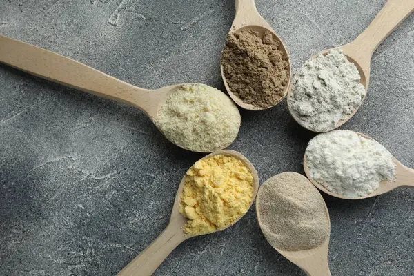 Gri masadaki kaşıklarda farklı türde un, düz.