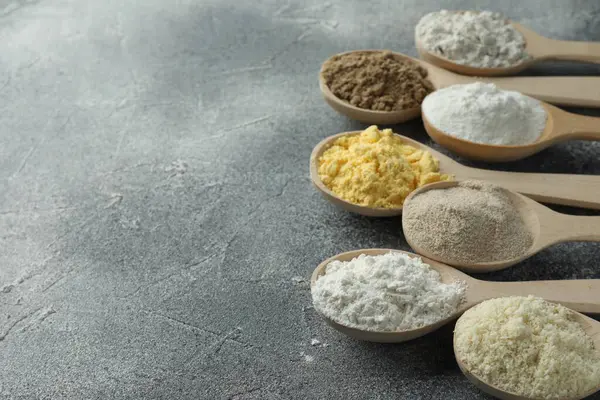 Gri masadaki kaşıklarda farklı türde un, yakın plan. Metin için boşluk