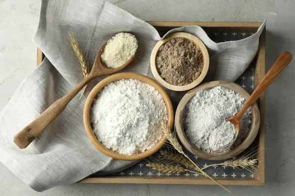 Açık gri masa üzerinde farklı un türleri, üst görünüm