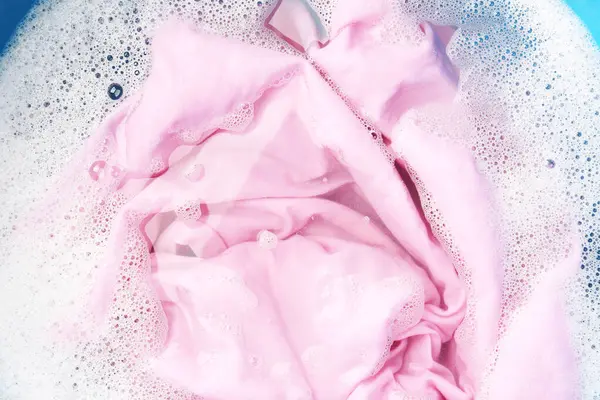 Pink clothes soaked in water before washing, top view