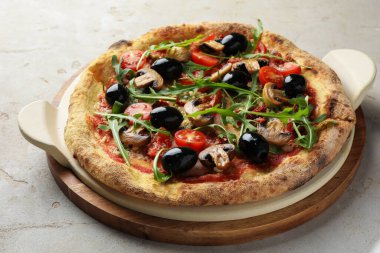 Mantarlı lezzetli pizza, siyah zeytin ve açık gri masada roka, yakın plan.