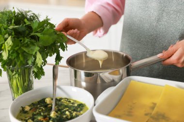 İçerideki masada ıspanaklı lazanya yapan kadın, yakın plan.
