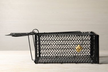 One metal mouse trap with bait on light wooden table