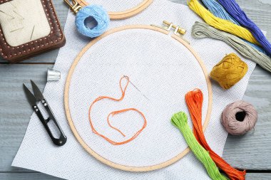 Gri ahşap masaya nakış işlemek için farklı dikiş malzemeleri.