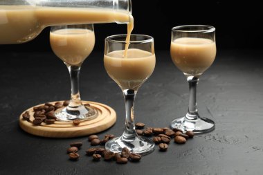 Siyah masada bardağa kremalı likör dökmek, yakın plan.