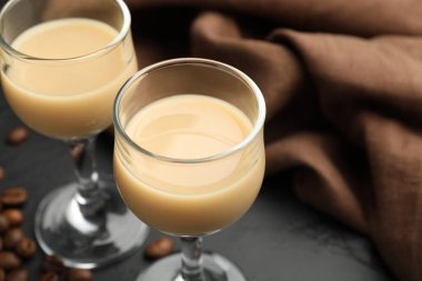 Bardakta kremalı kahve likörü ve siyah masada fasulye, yakın plan. Metin için boşluk