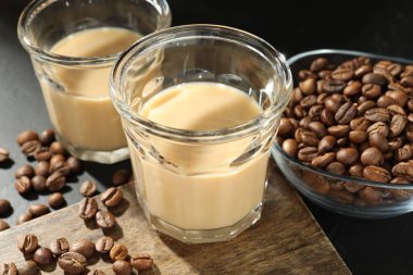 Bardakta kremalı kahve likörü ve siyah masada fasulye, yakın plan.