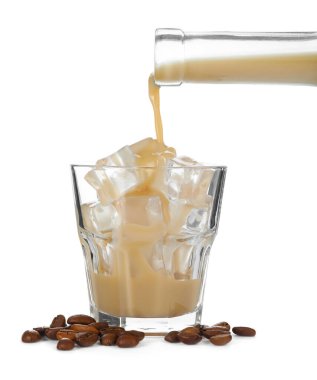 Pouring coffee cream liqueur from bottle into glass isolated on white