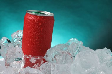 Refreshing drink in can on ice cubes against teal background, closeup