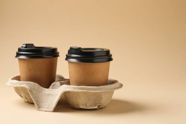 Kağıt kahve bardakları bej arka planda karton tutacakta. Metin için boşluk