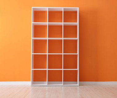 Turuncu duvarın yanındaki boş raf ünitesi.
