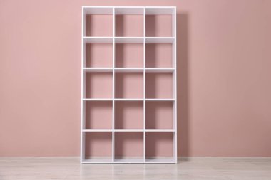 Pembe duvarın yanındaki boş raf ünitesi.