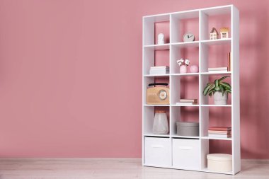 İçeride pembe duvarın yanında dekorasyonu olan raf ünitesi. Metin için boşluk