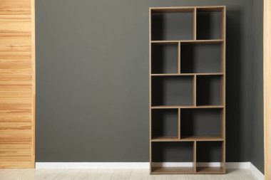 Boş raf ünitesi ve gri duvarın yanında katlanan ekran, metin için boşluk