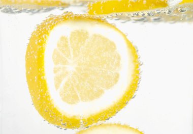 Arka planda limon dilimleri olan soda, yakın plan.