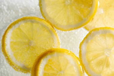 Arka planda limon dilimleri olan soda, yakın plan.