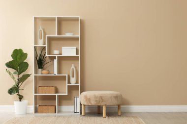 İçerideki bej duvarın yanında dekorlu ve sedirli raf ünitesi, metin için boşluk