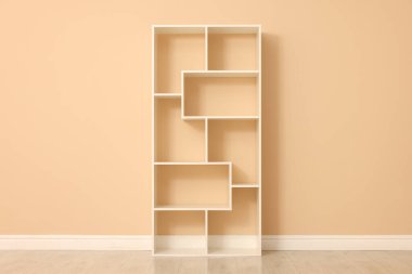 Bej duvarın yanındaki boş raf ünitesi.