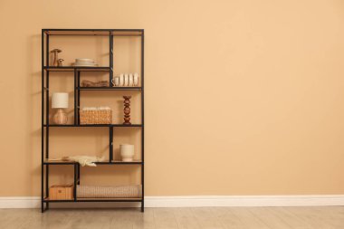 Shelving unit with decor near beige wall indoors, space for text