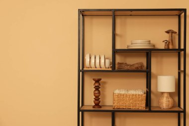 Shelving unit with decor near beige wall indoors, space for text