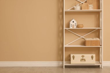 Shelving unit with decor near beige wall indoors, space for text