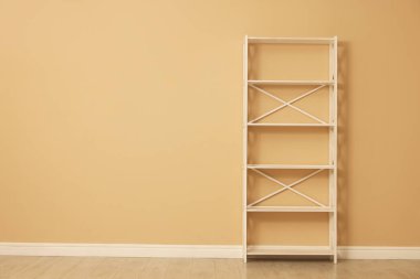 Empty shelving unit near beige wall indoors, space for text