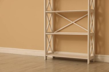 Bej duvarın yanındaki boş raf ünitesi.