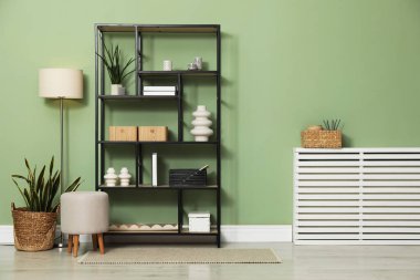 Salon içinde zeytin duvarının yanında farklı dekorasyonu olan ahşap raf ünitesi.