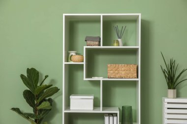 Salon içinde zeytin duvarının yanında farklı dekorasyonu olan ahşap raf ünitesi.