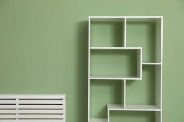 İçerideki zeytin duvarının yanındaki boş ahşap raf ünitesi.