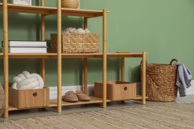 Salon içinde zeytin duvarının yanında farklı dekorasyonu olan ahşap raf ünitesi.