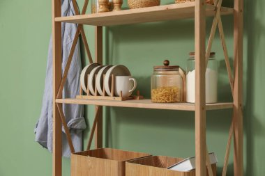 İçerideki zeytin duvarının yanında farklı dekorasyona sahip ahşap raf ünitesi, yakın plan.