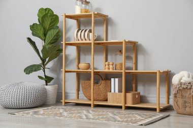 Açık gri duvarın yanında farklı dekorasyona sahip ahşap raf ünitesi.