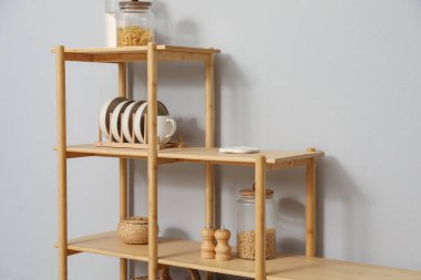 Açık gri duvarın yanında farklı dekorasyona sahip ahşap raf ünitesi.