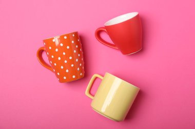 Pembe arka planda bir sürü renkli fincanlar var.