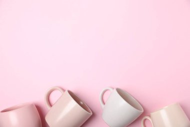 Pembe arka planda bir sürü renkli fincanlar, düz yatış. Metin için boşluk