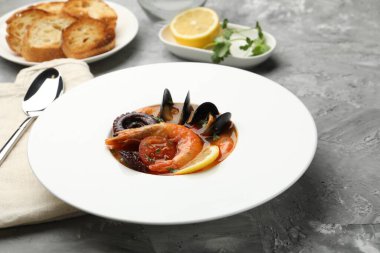 Gri desenli masada servis edilen lezzetli deniz ürünleri çorbası, yakın plan.