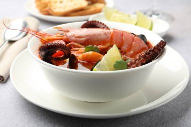 Açık gri masada servis edilen lezzetli deniz ürünleri çorbası, yakın plan.